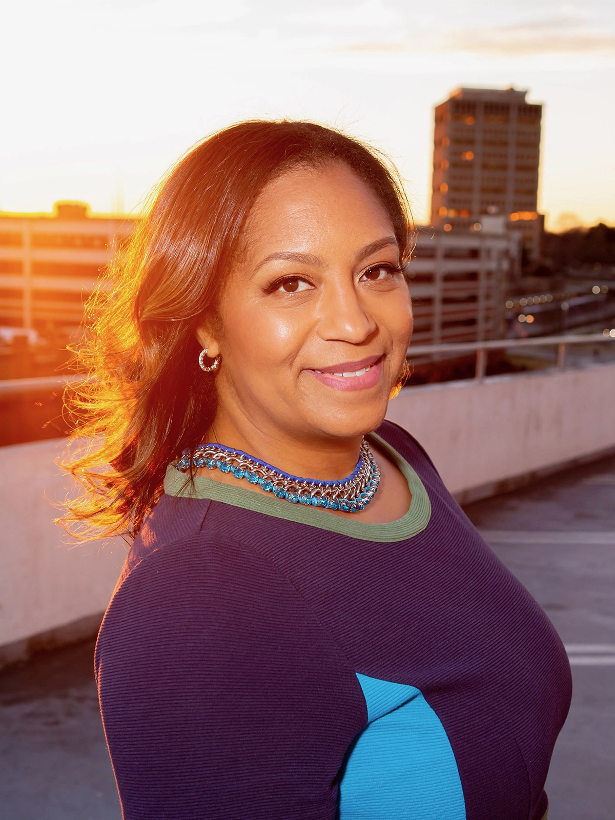 Reyna Walters-Morgan standing atop a parking deck with the glow from the sunlight illuminating her.